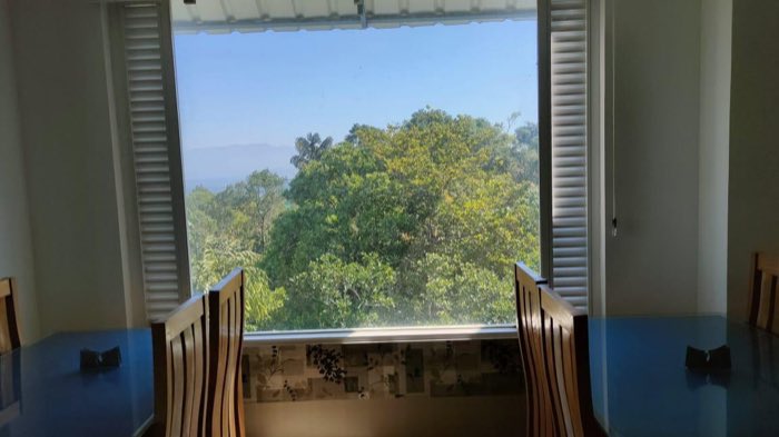 Green wooded hills and distant mountains seen through a wide window at Vanyora.