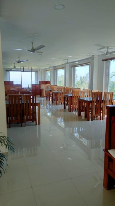 The Vanyora dining room, with rows of teak tables and chairs and a long wall of windows down one side.